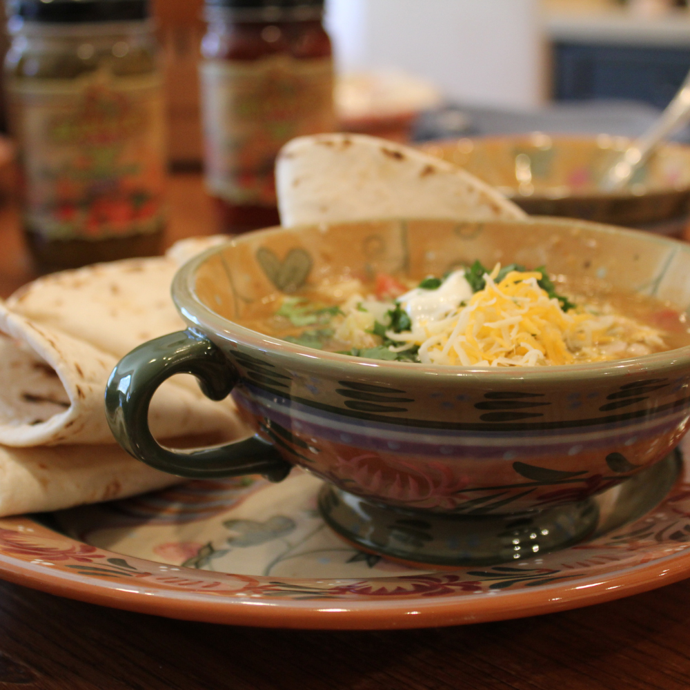 A steaming bowl of Gilly Loco Green Chile Stew, filled with tender chunks of meat, potatoes, and vibrant green chile, garnished with fresh cilantro