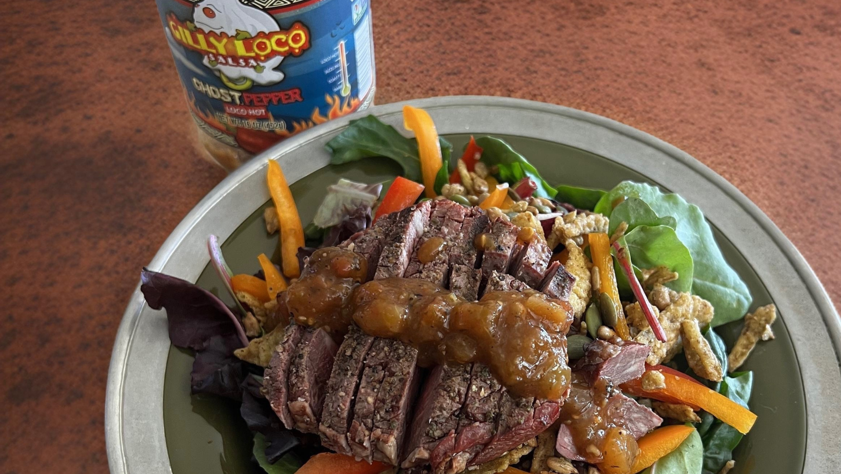 Photo of a vibrant homemade salad topped with Gilly Loco Ghost Pepper Salsa.