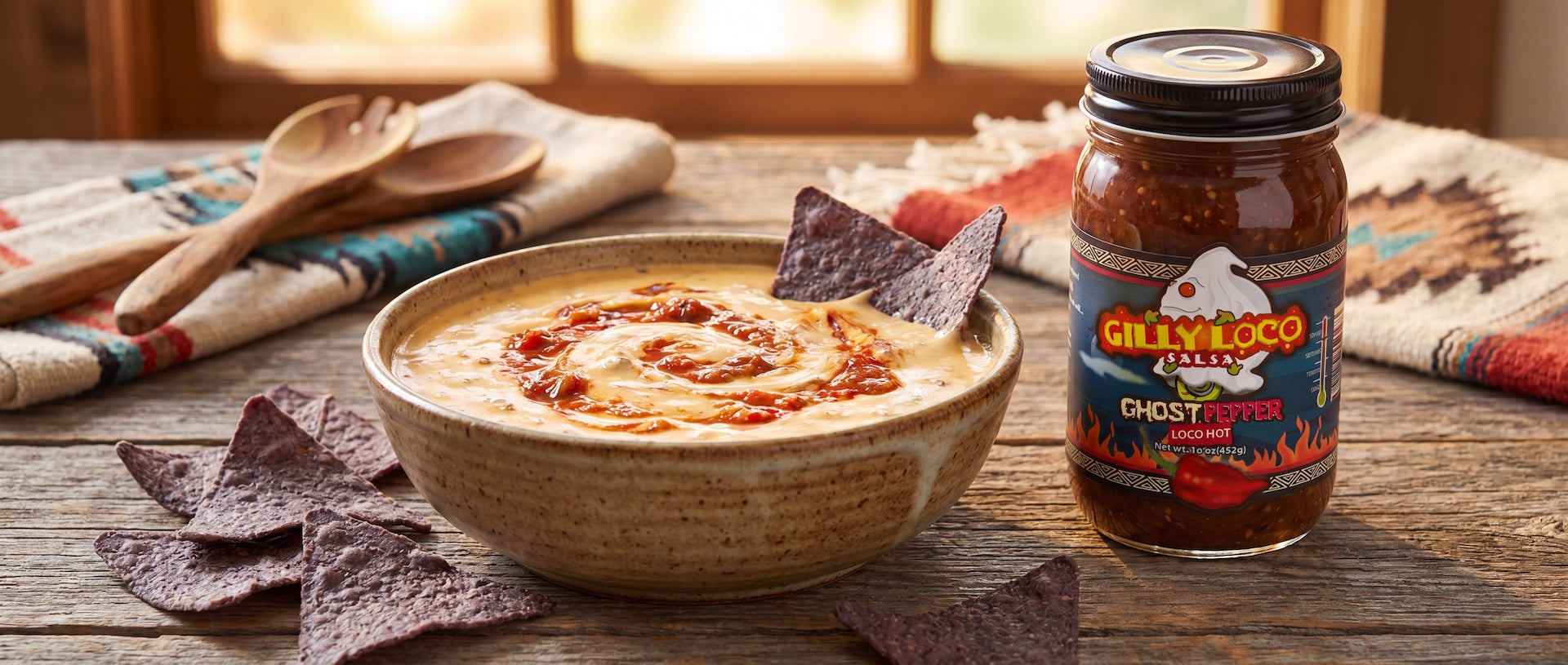 Creamy queso dip made with Gilly Loco Ghost Pepper Salsa, served with blue corn tortilla chips on a rustic wooden table.