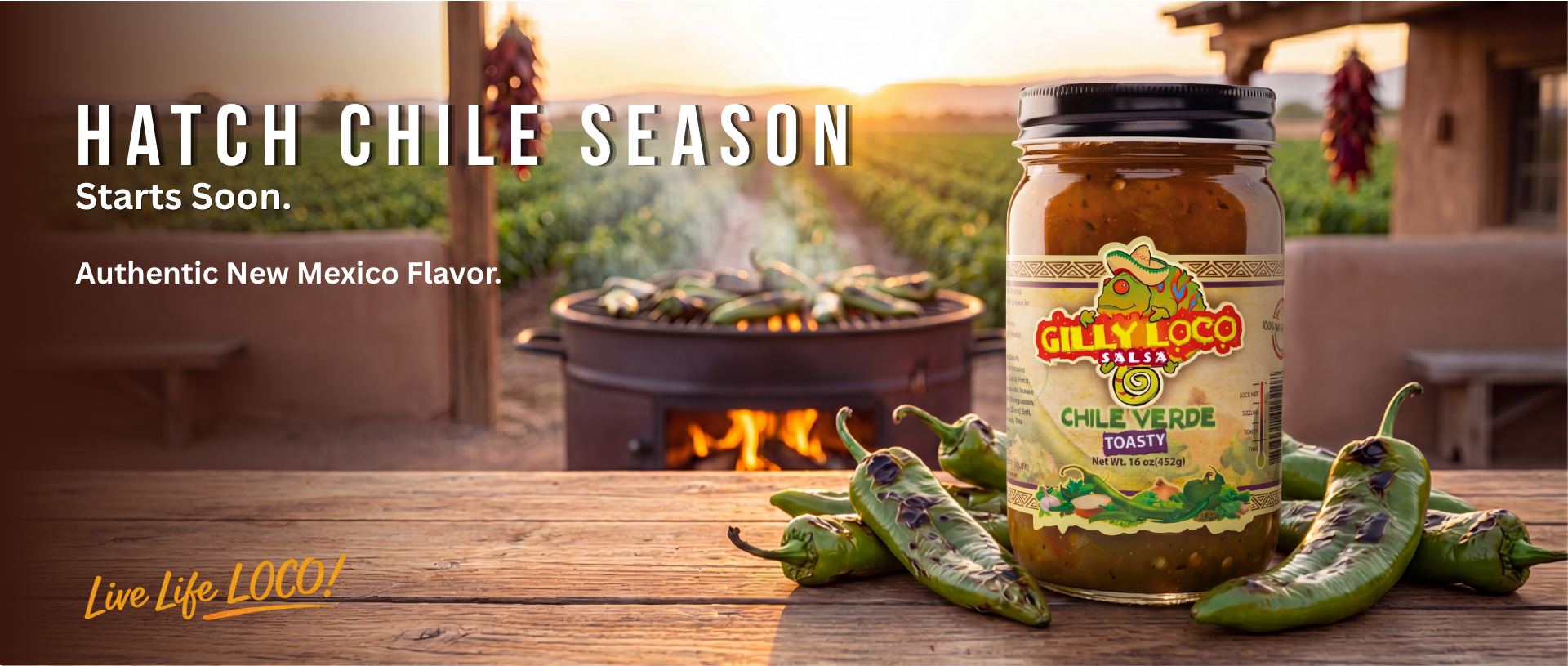 Jar of Gilly Loco Hatch Green Chile Sauce in front of roasting Hatch chiles at sunset during New Mexico Hatch chile season.