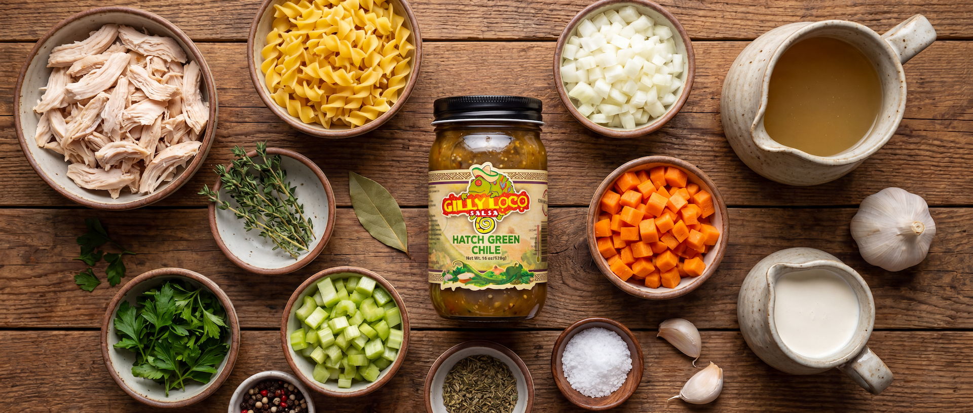 Flat lay of ingredients for New Mexico Hatch Green Chile Chicken Noodle Soup with shredded chicken, vegetables, noodles, herbs, and Gilly Loco Hatch Green Chile Sauce.